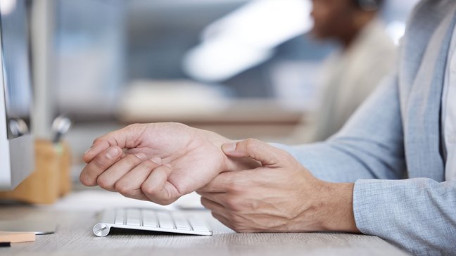 Orthopädiezentrum Wien - Hand-Mausarm bei einer Person, die ihr Handgelenk hält