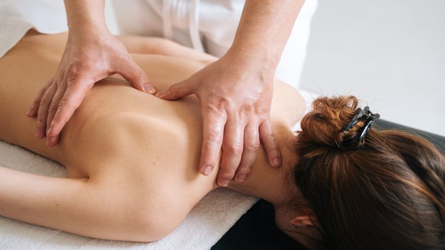 Orthopädiezentrum Wien - Therapeut führt Massagetherapie im Rahmen einer manuellen Behandlung an einer Patientin aus.