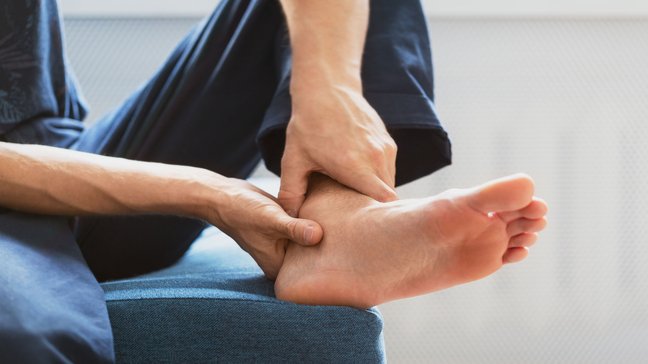 Orthopädiezentrum Wien - Eine Person massiert das Sprunggelenk aufgrund von Beschwerden durch Impingement.