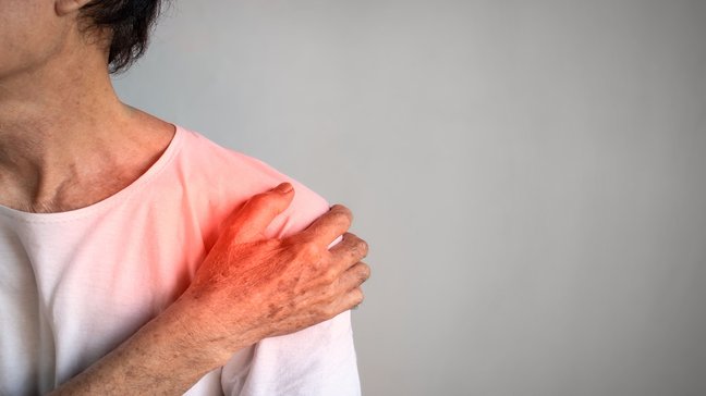 Orthopädiezentrum Wien - Älterer Mann greift sich an die Schulter, möglicherweise aufgrund einer Frozen Shoulder.