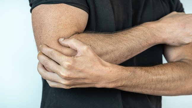 Orthopädiezentrum Wien - Mann hält seinen Ellenbogen aufgrund eines Olecranonsporns