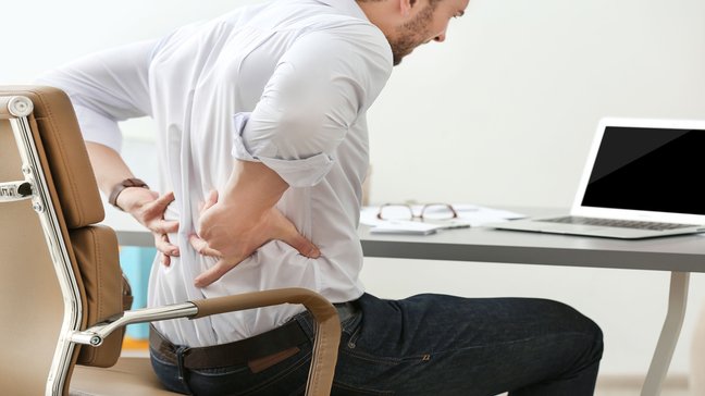 Orthopädiezentrum Wien - Mann mit Spondylolisthesis, der Rückenschmerzen im unteren Rücken spürt.