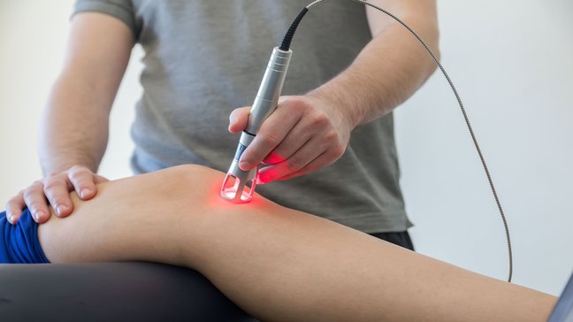 Orthopädiezentrum Wien - Mann führt Laserbehandlung im Rahmen einer Physikalischen und Elektrotherapie durch